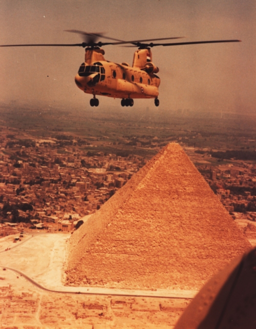 A photograph of a Chinook helicopter flying near the Great Pyramids of Egypt.
