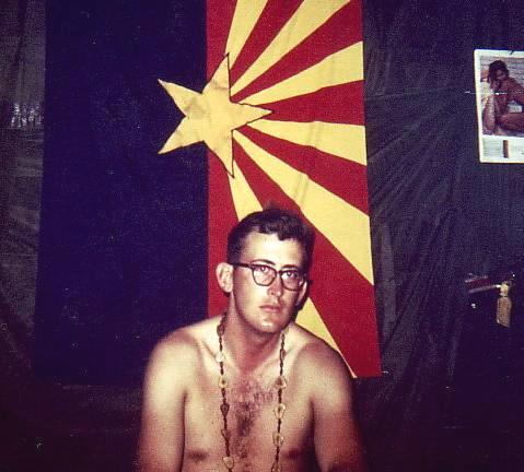 David Petty II, the Crew Chief (CC) and Right Door Gunner (DG) during the crash of the "Pusher" in Cambodia. Note the Arizona state flag behind him which was often mistaken for a Vietcong flag.