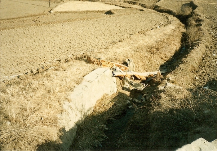 A large section of a rotor blade from a UH-60 Blackhawk helicopter resting in a ditch after the wire strike.