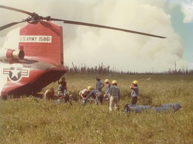 CH-47C Chinook helicopter 68-15861 at a remote location in Alaska supporting fire fighting efforts. Bureau of Land Management (BLM) personnel can be seen unloading supplies and equipment needed to fight the tundra fire. Smoke from the fire can be seen rising in distance.