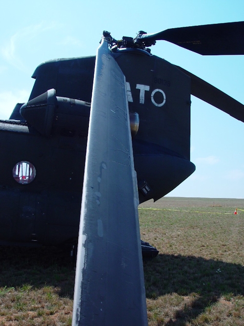 July 2002: Sitting in the grass at Camp Bondsteel, Serbia, this photograph shows 89-00138 the day after the accident. An aft rotor system blade lead-lag dampner lug has broken off allowing the blade to droop excessively low where it came in to contact with the fuselage and damaged the structure.