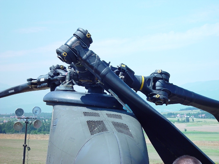 July 2002: This photograph shows extensive damage to the aft rotor system. A lead-lag dampner has broken off allowing the green blade to strike the fuselage and ground. All blades on a Chinook rotor system are color coded - Red, Green, or Yellow.  Look for the paint stripe on the rotor head - the yellow stripe is easily visible.