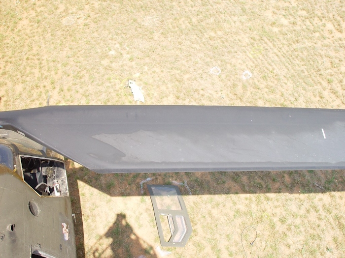 July 2002: A birds eye view of the top of a forward rotor blade. The right cockpit door is laying on the ground as well as some debris from the helicopter (forward of the blade).