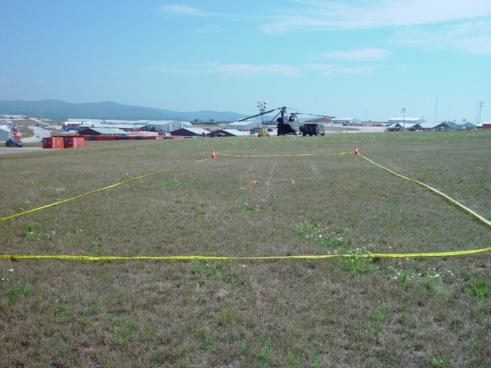 6 July 2002: A view of the landing site and initial touchdown zone area during the crash sequence. Yellow plastic tape cordons off the marks still visible in the grass where 89-00138 made first contact with the ground during the event.