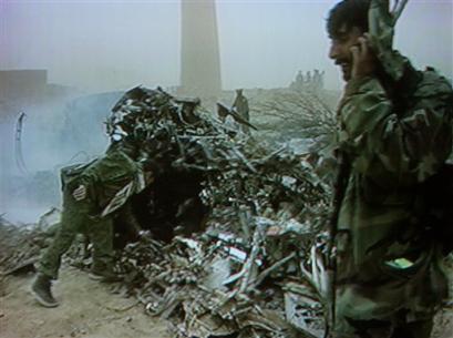 In this image taken from video, Afghan security forces inspect the wreckage of a U.S. military CH-47D Chinook helicopter.