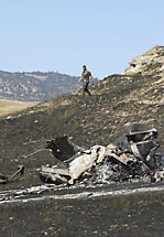 A soldier examines the wreckage of an Army helicopter after it crashed.