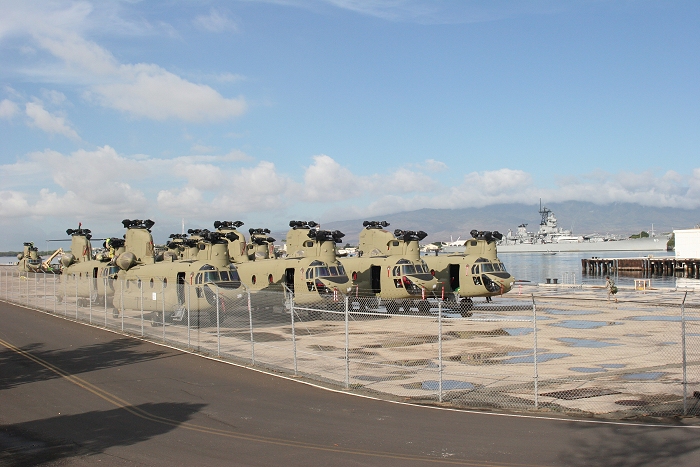 19 November 2010: CW4 Jack Tartaglia walks past fourteen CH-47F Chinook helicopters awaiting reassembly on the dock at Pearl Harbor. The USS Missouri rests silently in the background near the USS Arizona memorial.