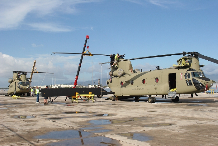 19 November 2010: Members of the Boeing Maintenance Team work on two Chinook helicopters, prepping them to fly off the dock at Pearl Harbor and head to Wheeler Army Airfield. In the background one can see the old control tower on Ford Island.