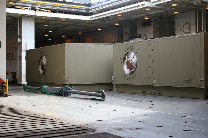 18 November 2010: One of two CH-47F Chinook helicopter Transportable Flight Proficiency Simulators (TPFS), along with the spreader bar used to sling the helicopter off the ship, sits below deck under the center cargo hole aboard the USNS Mendonca.