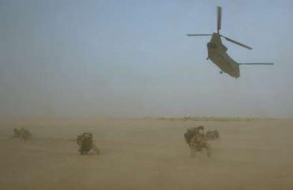 Soldiers of the 1st Battalion - The Parachute Regiment, protect themselves as a Chinook helicopter takes off during operations at their camp in southern Iraq on 29 March 2003.