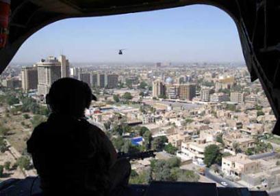 A United States Army CH-47D Chinook helicopter door gunner keeps watch while flying over the Iraqi capital of Baghdad.