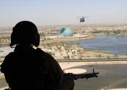 A United States Army CH-47D Chinook helicopter door gunner keeps watch while flying over the Iraqi capital of Baghdad.