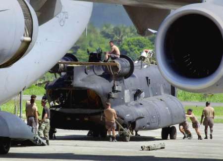 Soldiers push a disassembled U.S. Army MH-47E Chinook in preparation for loading aboard an Air Force C-17 transport aircraft.