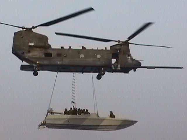 An unknown MH-47 Chinook helicopter slings a boat load of troops during an unknown mission, at an unknown location, and on an unknown date.