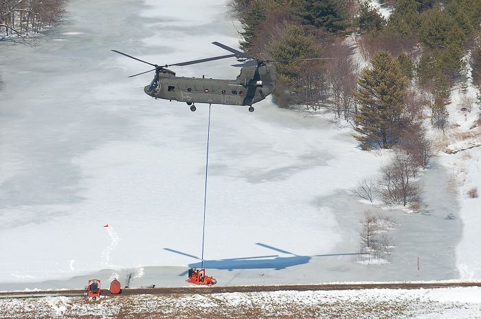 A Maryland Army National Guard CH-47D Chinook helicopter from Company B, 3rd battalion, 126th Aviation Regiment, assists local authorities by hauling two giant pumps used to relieve pressure on a dam in the western Maryland town of Oakland.