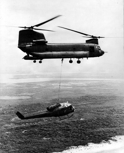 An unknown CH-47A Chinook helicopter lifts a disabled UH-1 Huey in the Republic of Vietnam.