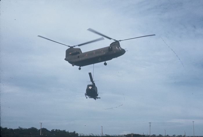 An unknown CH-47A Chinook helicopter lifts a disabled UH-1 Huey at Soc Trang in the Republic of Vietnam, date unknown.